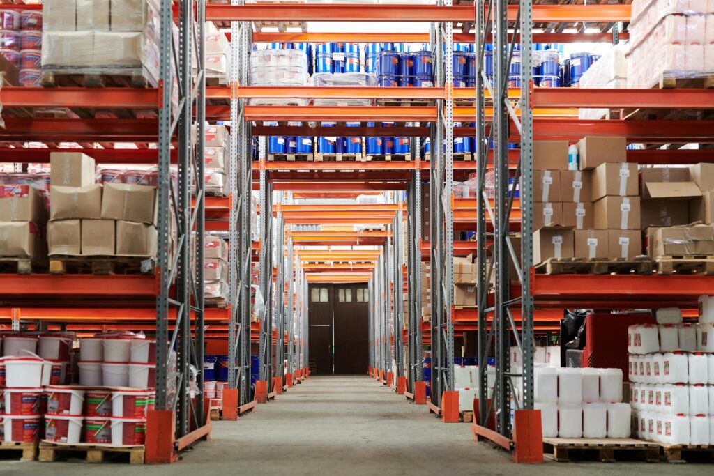 A large warehouse with neatly stacked shelves, showcasing organized inventory management, featuring pallets of boxes and containers for efficient storage